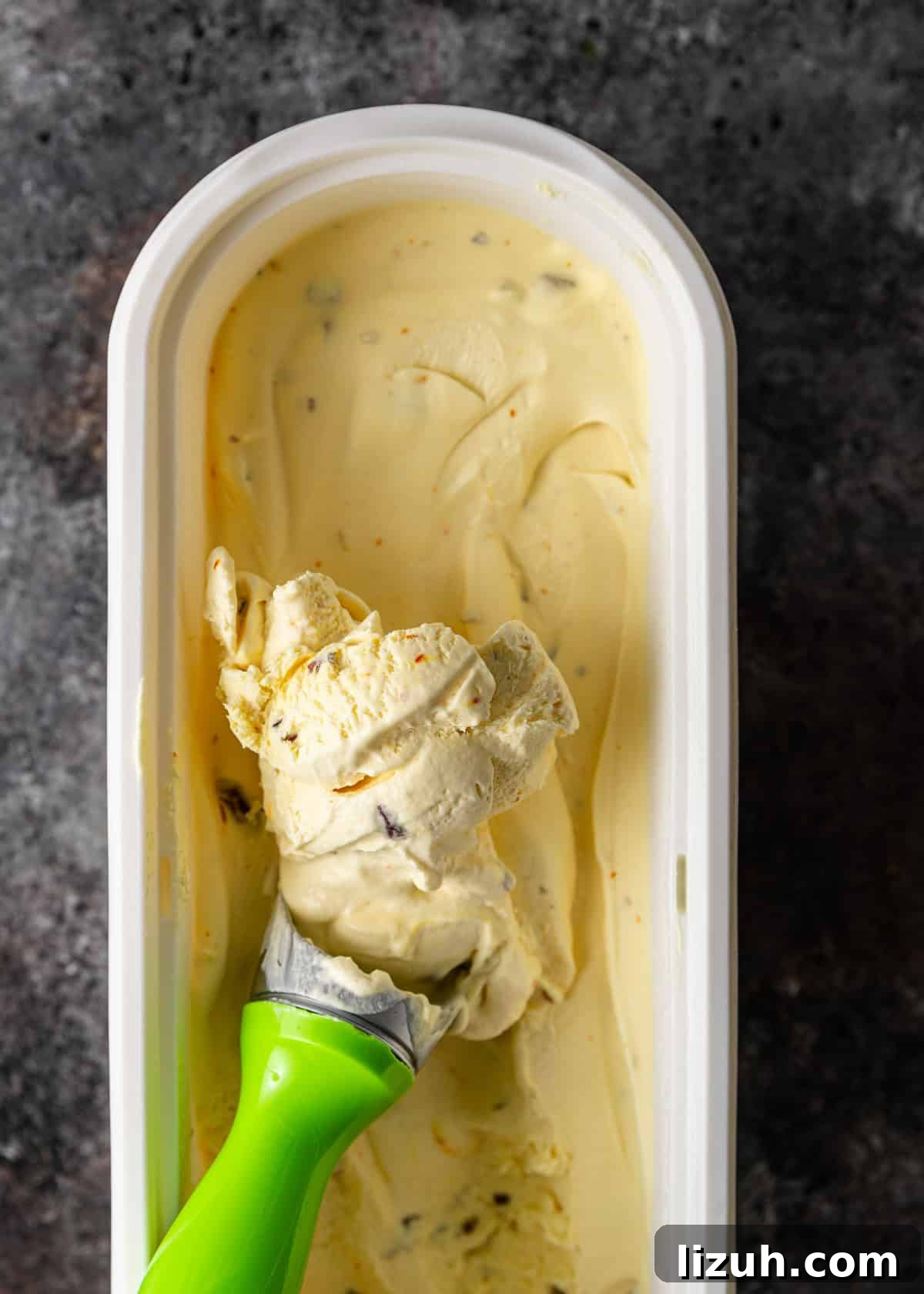 overhead: scooping out pistachio ice cream from the tub