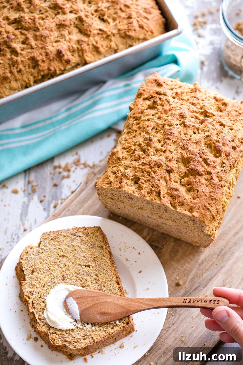 overhead of slice being spread with cream cheese with the rest of the loaf nearby