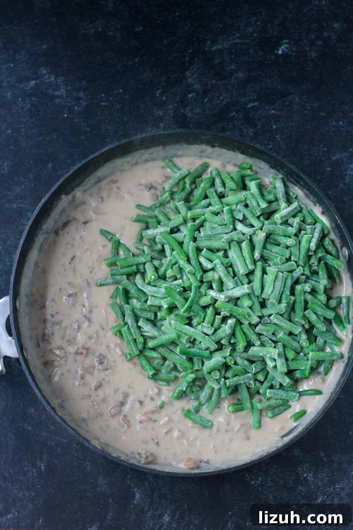 Adding frozen cut green beans to the mushroom sauce.
