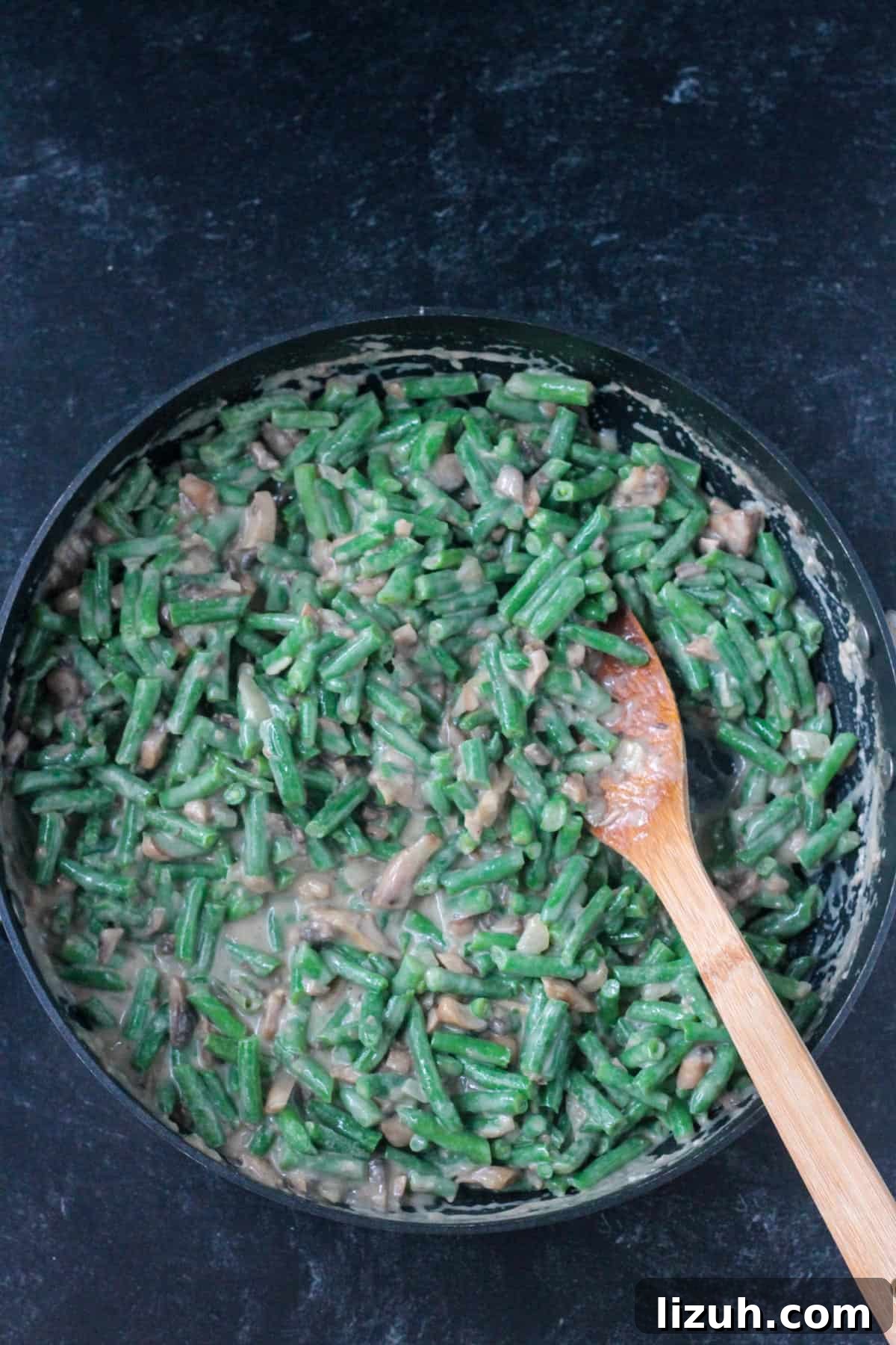 Mixing the green beans into the mushroom sauce.