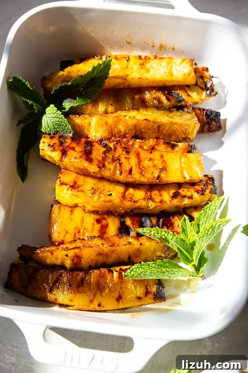 Brazilian-Style Grilled Pineapple Recipe for Sweet Tangy Dessert 6 Grilled Brazilian Pineapple in a white baking dish with fresh mint.