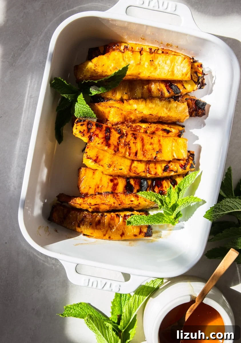 Brazilian-Style Grilled Pineapple Recipe for Sweet Tangy Dessert 7 Grilled Brazilian Pineapple with fresh mint in a white baking dish.