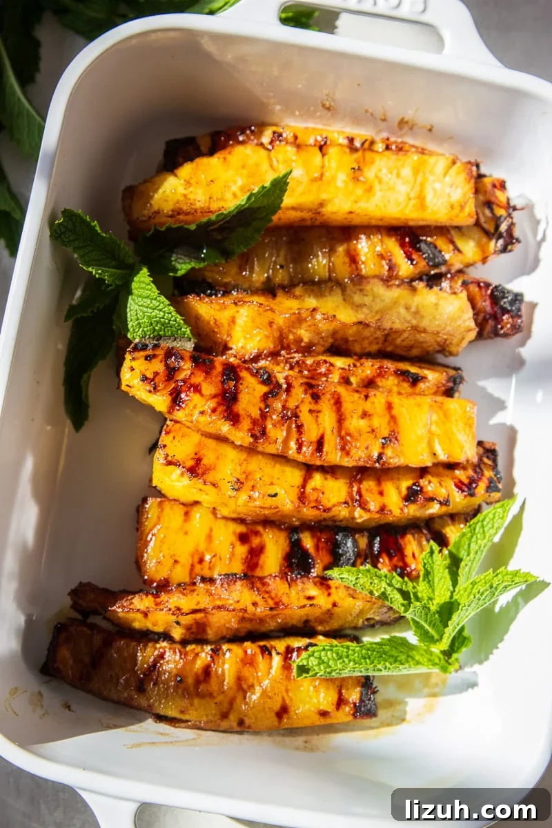 Brazilian-Style Grilled Pineapple Recipe for Sweet Tangy Dessert 8 Grilled Brazilian Pineapple with fresh mint in a white baking dish.