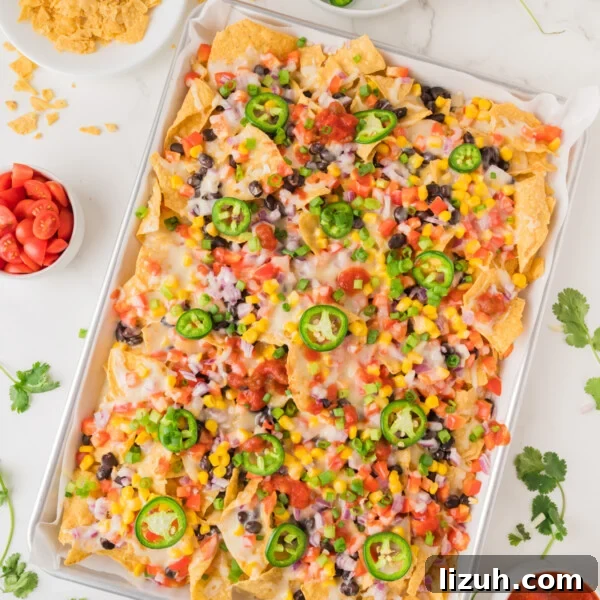 Loaded Tater Tot Nachos with Cheesy Beef and Jalapeños 11 An overhead image of vegetarian nachos on a sheet pan with toppings.