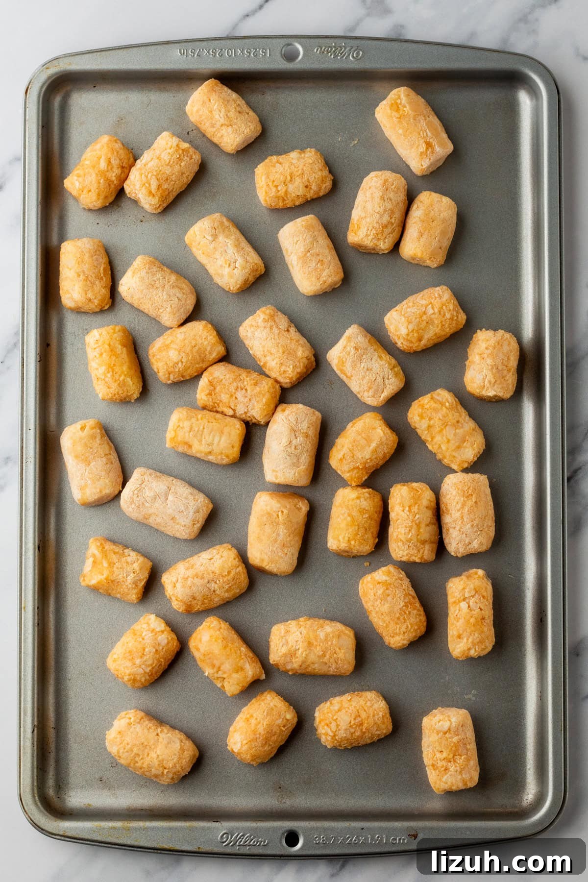 Loaded Tater Tot Nachos with Cheesy Beef and Jalapeños 4 An overhead image of spreading tater tots on a baking sheet.