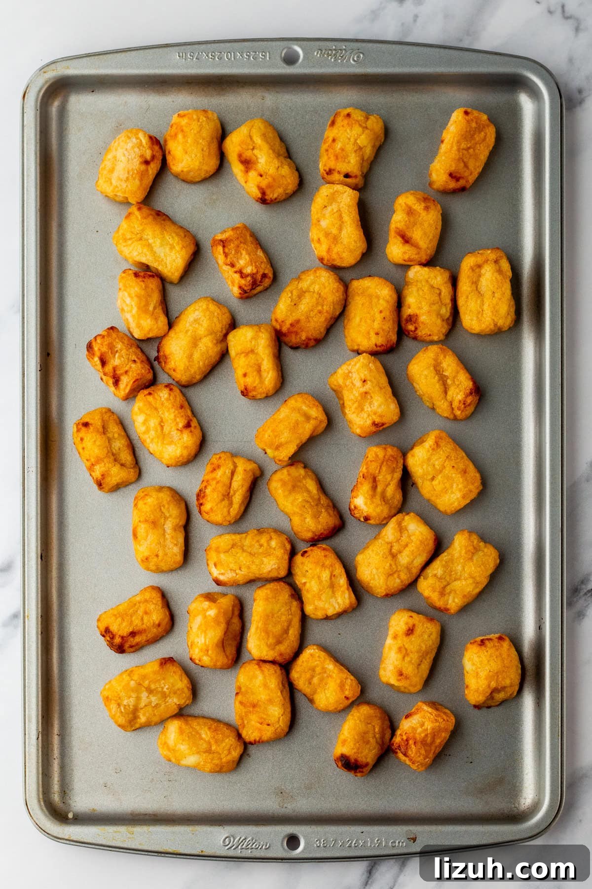 Loaded Tater Tot Nachos with Cheesy Beef and Jalapeños 5 An overhead image of baked tater tots on a sheet pan.
