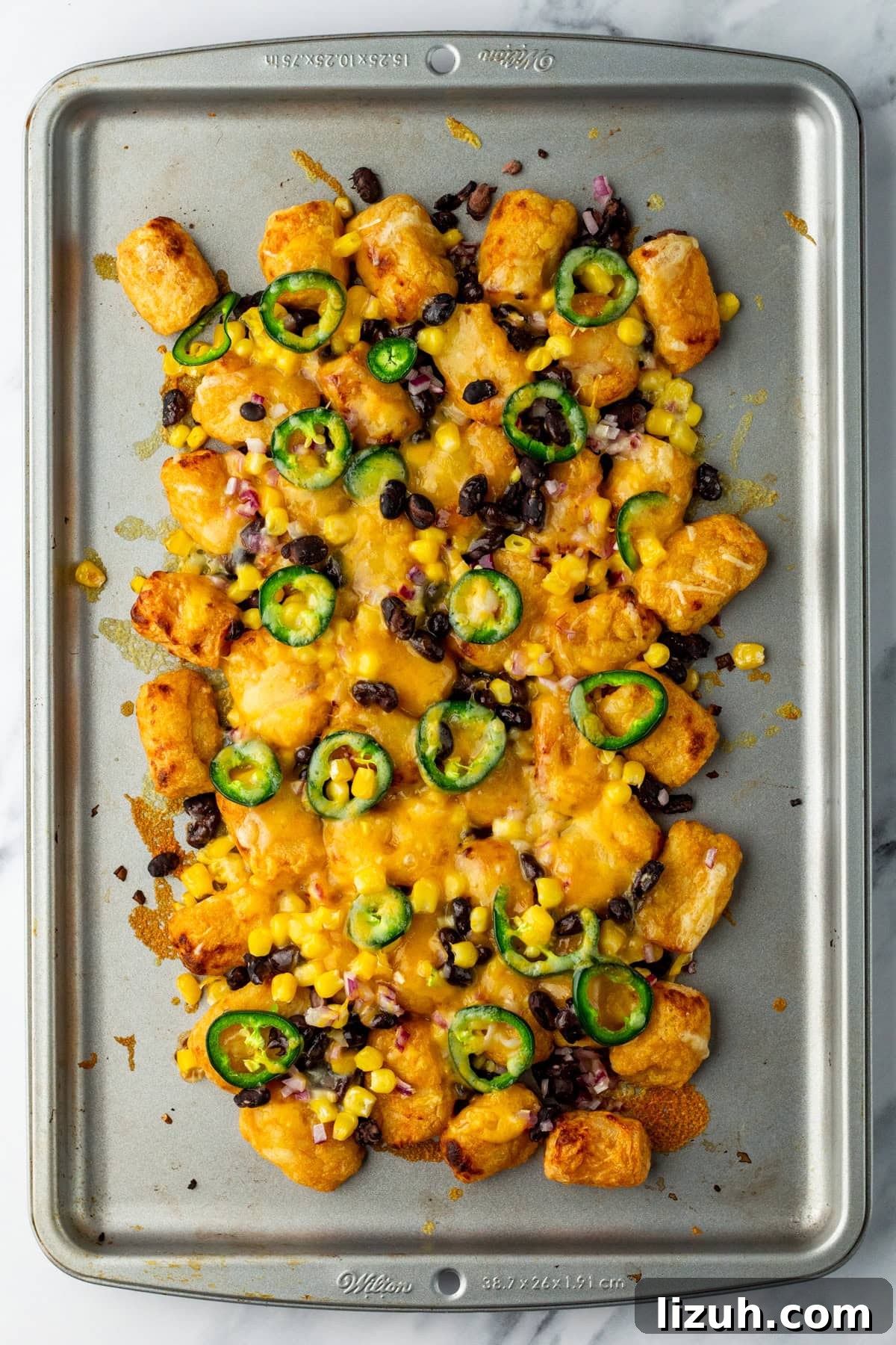 Loaded Tater Tot Nachos with Cheesy Beef and Jalapeños 8 An overhead image of the melted cheese on top of the tater tots.