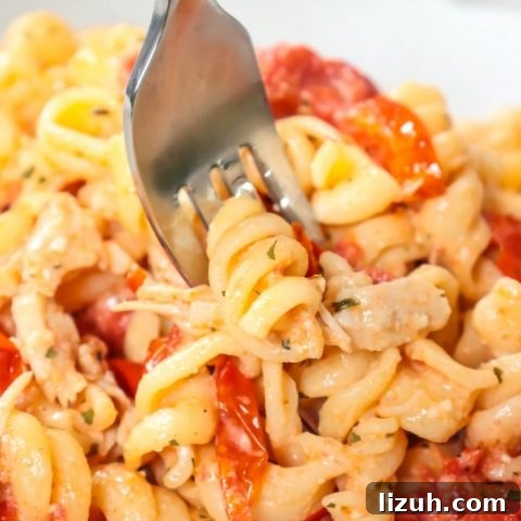 Fork full of of BAKED CHICKEN FETA PASTA – TIKTOK PASTA RECIPE on white plate