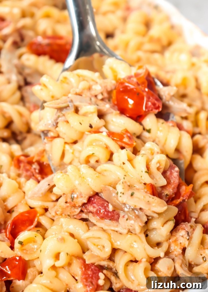 Baked Chicken and Feta Pasta TikTok Recipe 9 Giant spoonful of BAKED CHICKEN FETA PASTA – TIKTOK PASTA RECIPE on white plate
