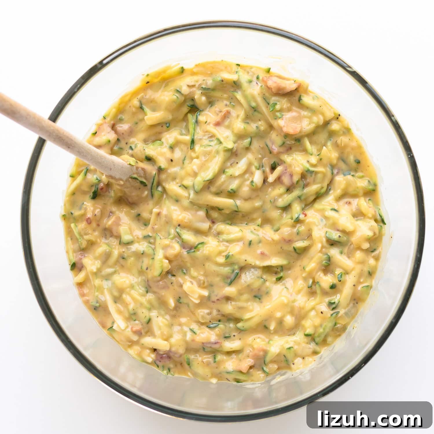Savory Zucchini Slice Recipe with Cheesy Herb Crust 7 Zucchini slice batter in a glass mixing bowl with wooden spoon.