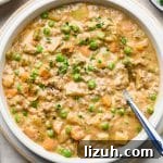 A bowl of thick and creamy shepherds pie soup, with a hand tucking a spoon into the soup to scoop some up.