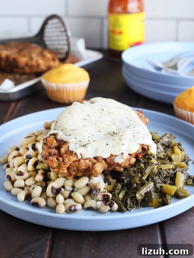 Back-to-School Dinner Ideas: Quick Family-Friendly Recipes 12 Chicken fried steak topped with country gravy on a plate with a pile of black-eyed peas and turnip greens.