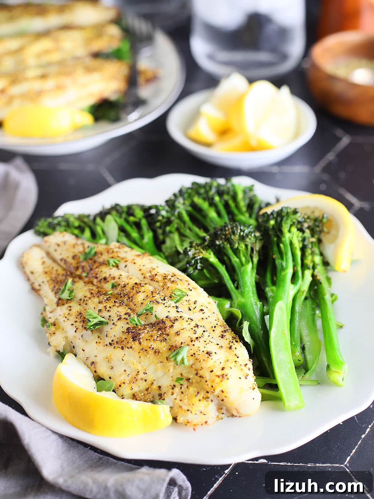 Back-to-School Dinner Ideas: Quick Family-Friendly Recipes 15 Lemon pepper air fryer catfish fillet on a plate with broccolini and lemon wedges.