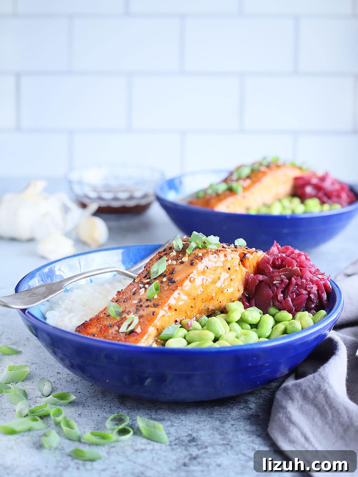 Back-to-School Dinner Ideas: Quick Family-Friendly Recipes 6 Filet of air fryer teriyaki salmon in a bowl with white rice, shelled edamame and pickled cabbage.