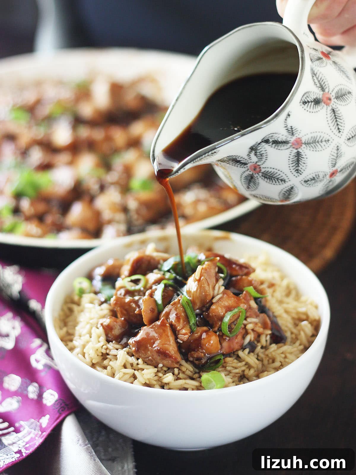 Back-to-School Dinner Ideas: Quick Family-Friendly Recipes 9 Hand pouring teriyaki sauce over a bowl of bourbon chicken served over rice.