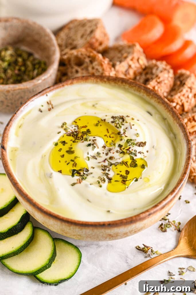 High-protein cottage cheese dip garnished with herbs and olive oil, perfect for dipping with bread, carrots, and zucchini.