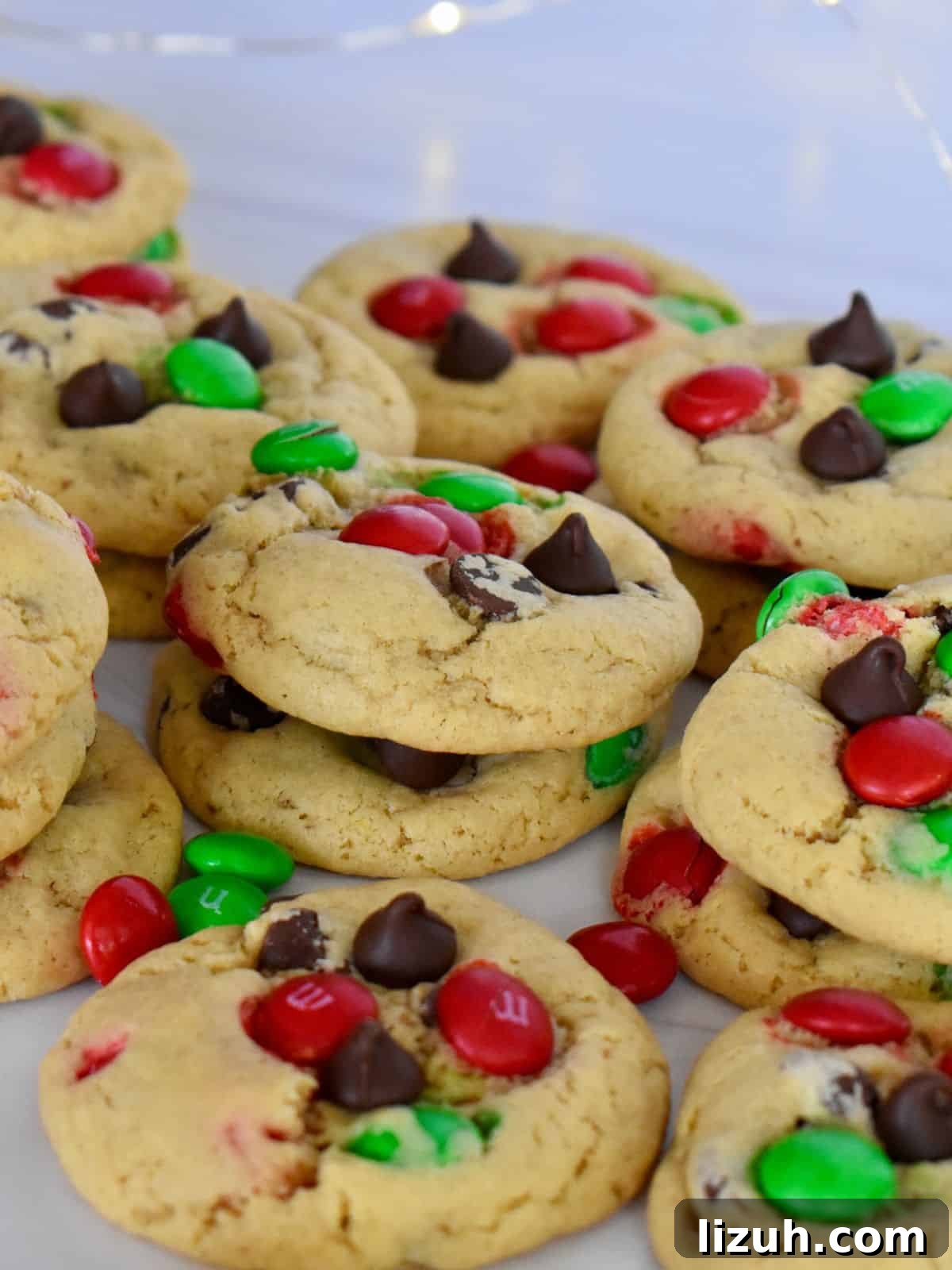 Christmas M&M Cookies Recipe: Festive, Chewy Holiday Cookies 8 Christmas M&M Cookies on a white surface with chocolate chips.