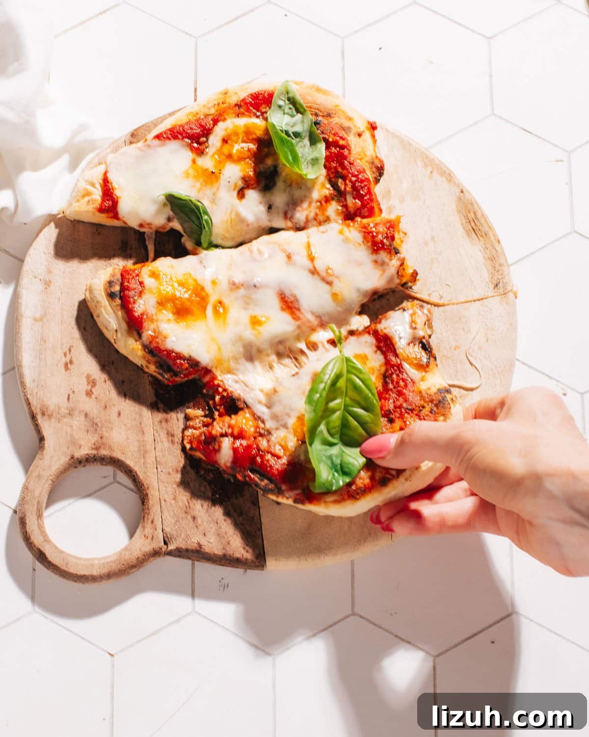 15-Minute Naan Pizza Recipe: Quick Homemade Pizza on Naan 7 Pulling off a piece of naan pizza.
