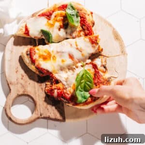 15-Minute Naan Pizza Recipe: Quick Homemade Pizza on Naan 8 Pulling off a piece of naan pizza.