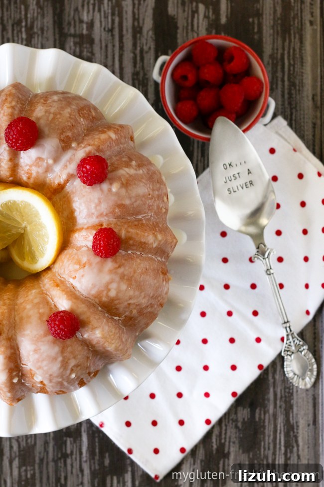 Gluten-Free Lemon Coconut Cake (Dairy-Free Recipe) 3 gluten-free lemon cake on platter with cake server beside it and raspberries