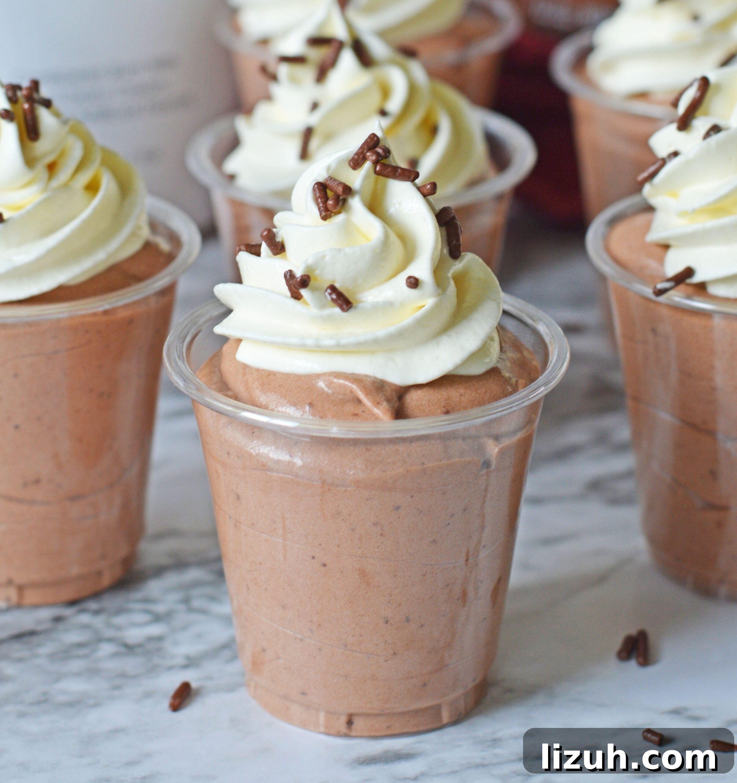 close up of the Rumchata pudding shots on a marble table topped with whipped cream and sprinkles
