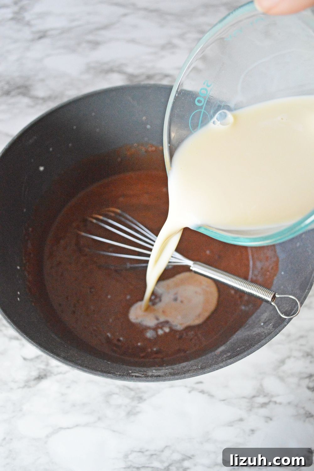 milk being poured into chocolate pudding mixture in bowl 