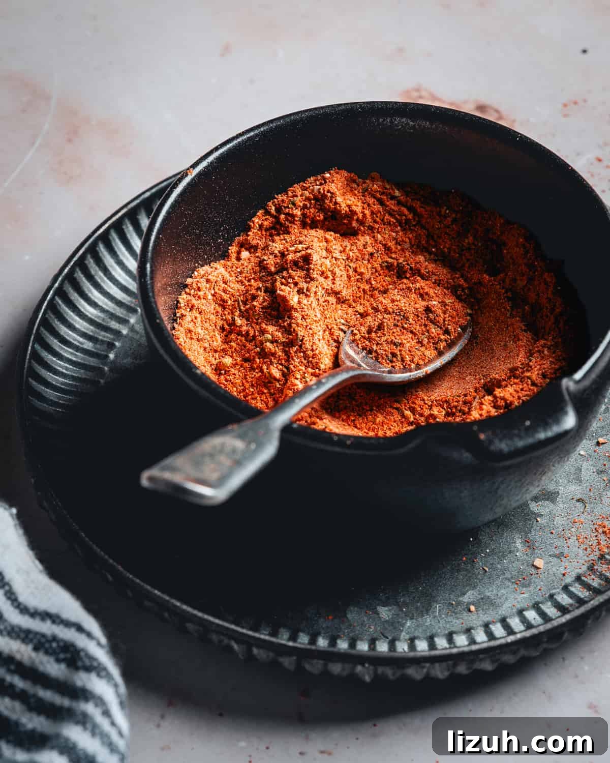 Homemade Blackened Seasoning Mix for Bold, Flavorful Dishes 2 Homemade Blackened Seasoning in a black bowl with a silver spoon photographed from the side.