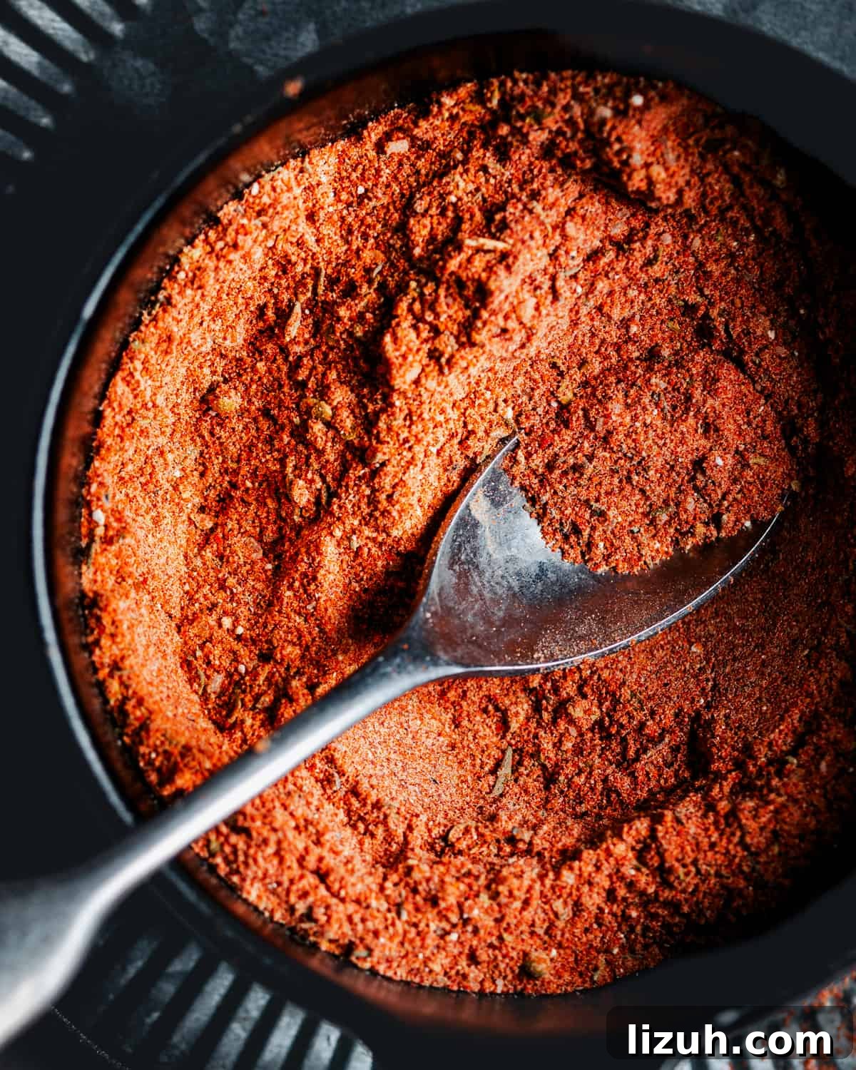 Homemade Blackened Seasoning Mix for Bold, Flavorful Dishes 5 A close up of Blackened Seasoning in a black bowl with a silver spoon photographed from the top.