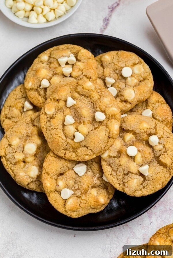Golden white chocolate chip cookies on a black plate