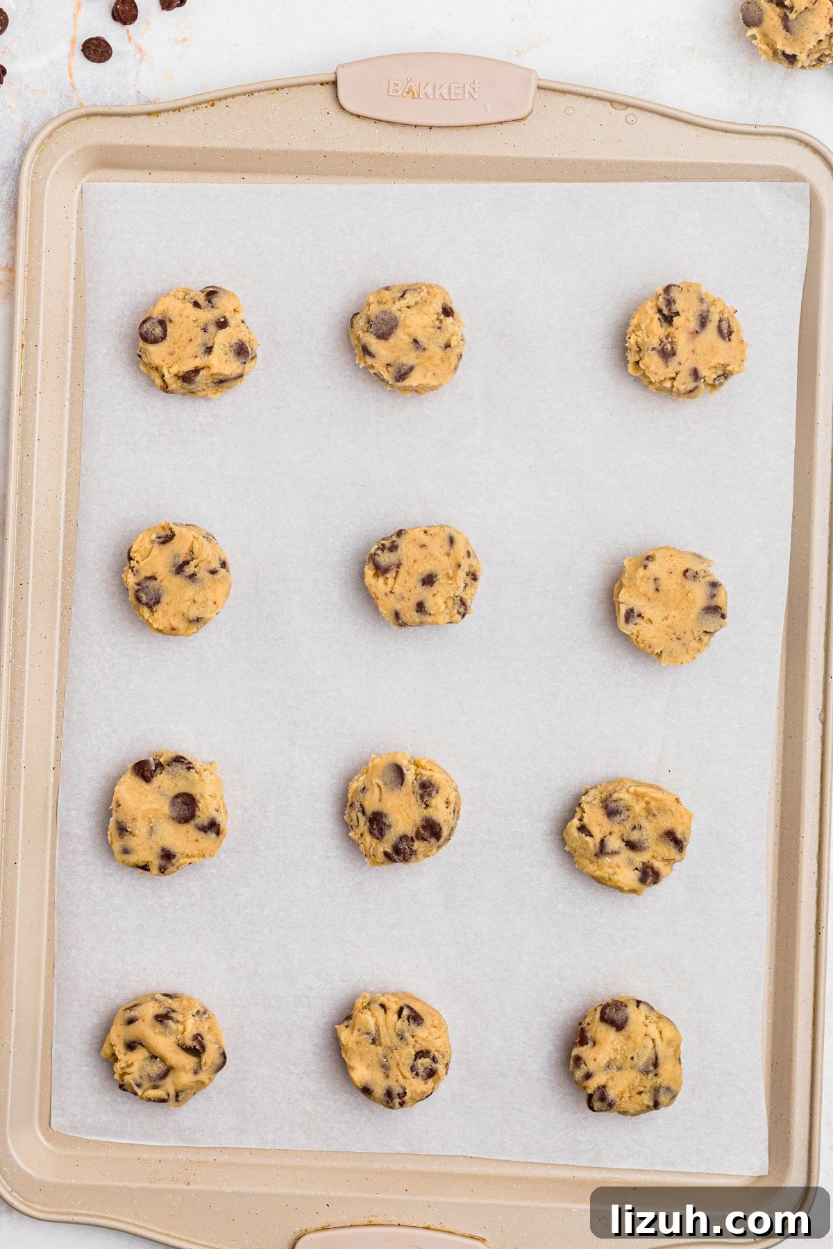 Cookie dough in small balls on a baking sheet lined with parchment paper. 