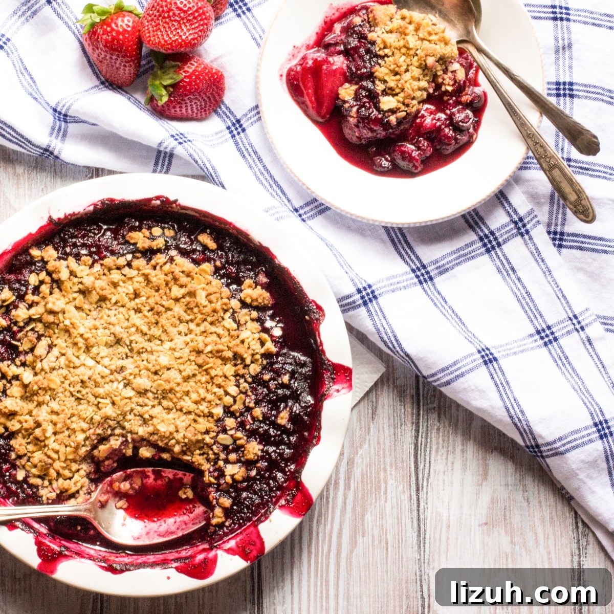 April Vegetarian Meal Plan: Week 4 Recipes & Grocery List 10 A pie plate of strawberry blueberry crumble with a small plate of a serving and a few fresh strawberries.