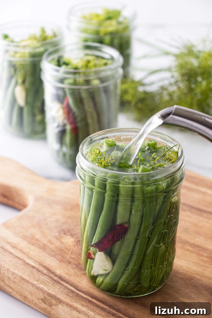 Adding the brine to a jar of hot pickled green beans.