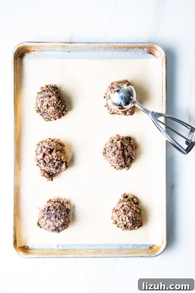 Black Bean Veggie Burger Recipe — Flavorful Homemade Patties 8 Scoops of veggie burger dough on a baking tray lined with parchment paper.