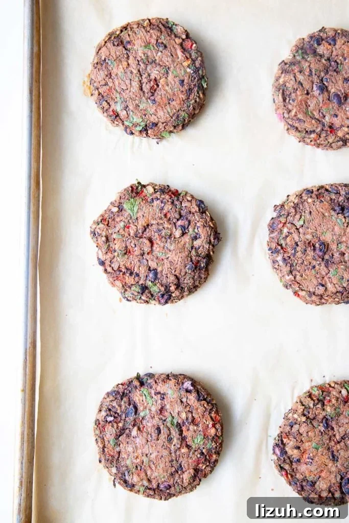 Black Bean Veggie Burger Recipe — Flavorful Homemade Patties 10 Cooked Veggie Burgers on a baking tray lined with parchment paper.