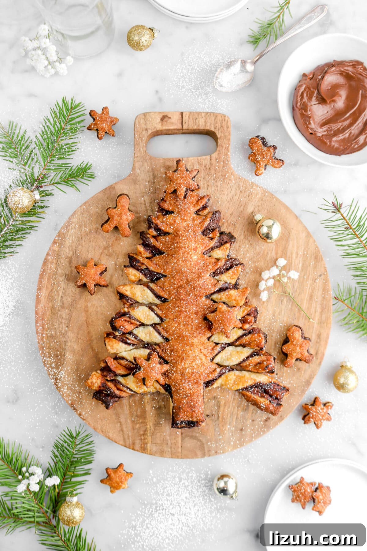 overhead shot of christmas tree tear and share on wood board with gold ornaments, pine branches, and bowl of ganache beside.