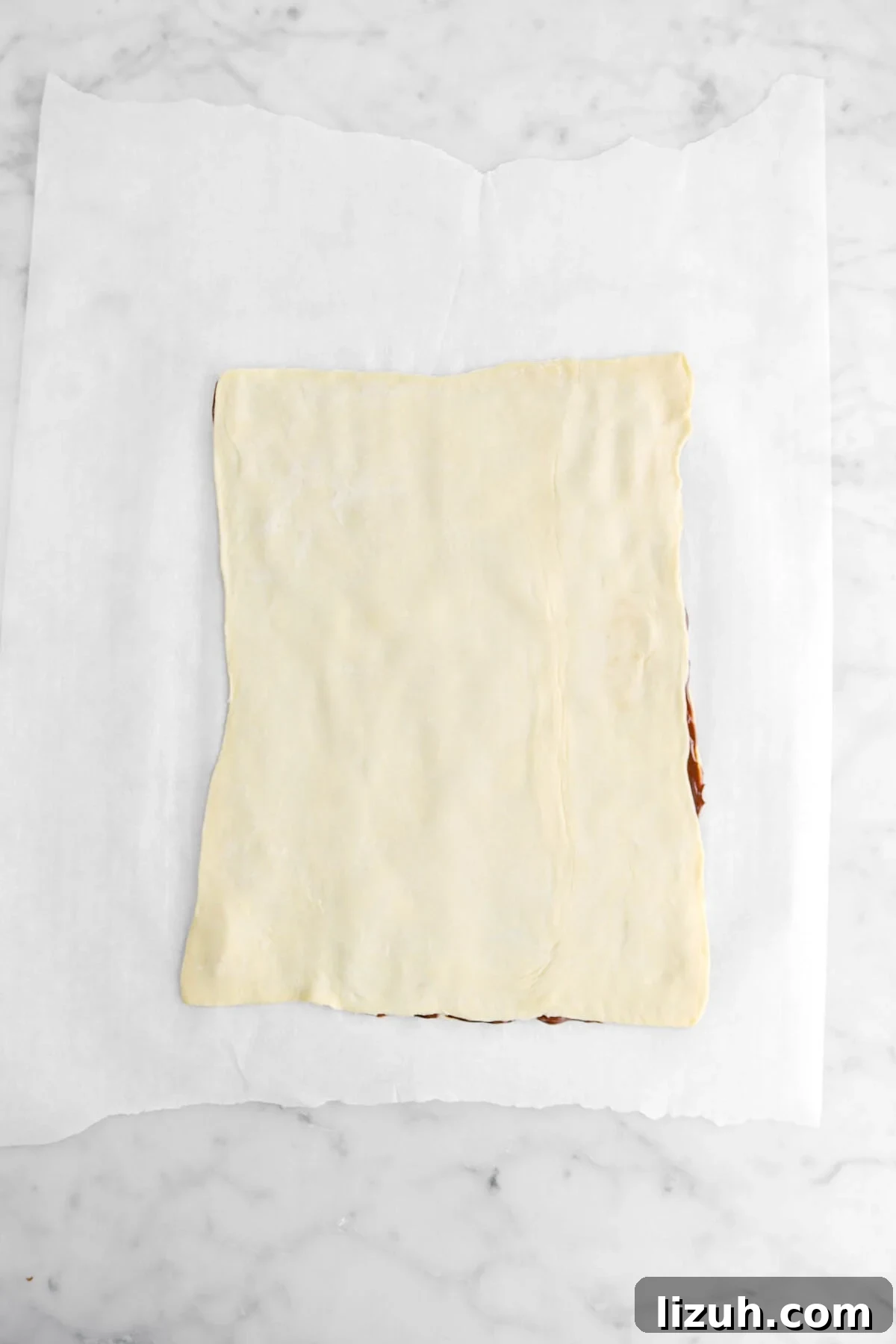 second sheet of rolled out puff pastry placed over chocolate ganache.