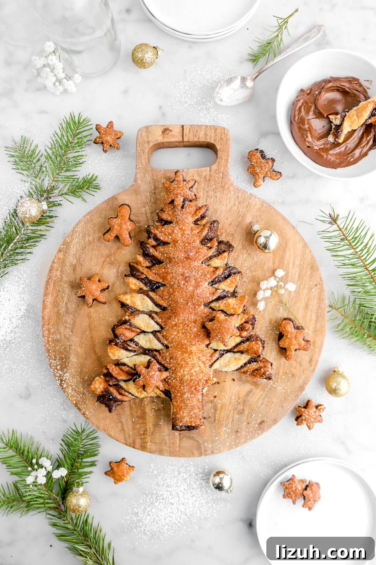 piece of tear and share in bowl of ganache beside wood board with christmas tree shaped tear and share on it.