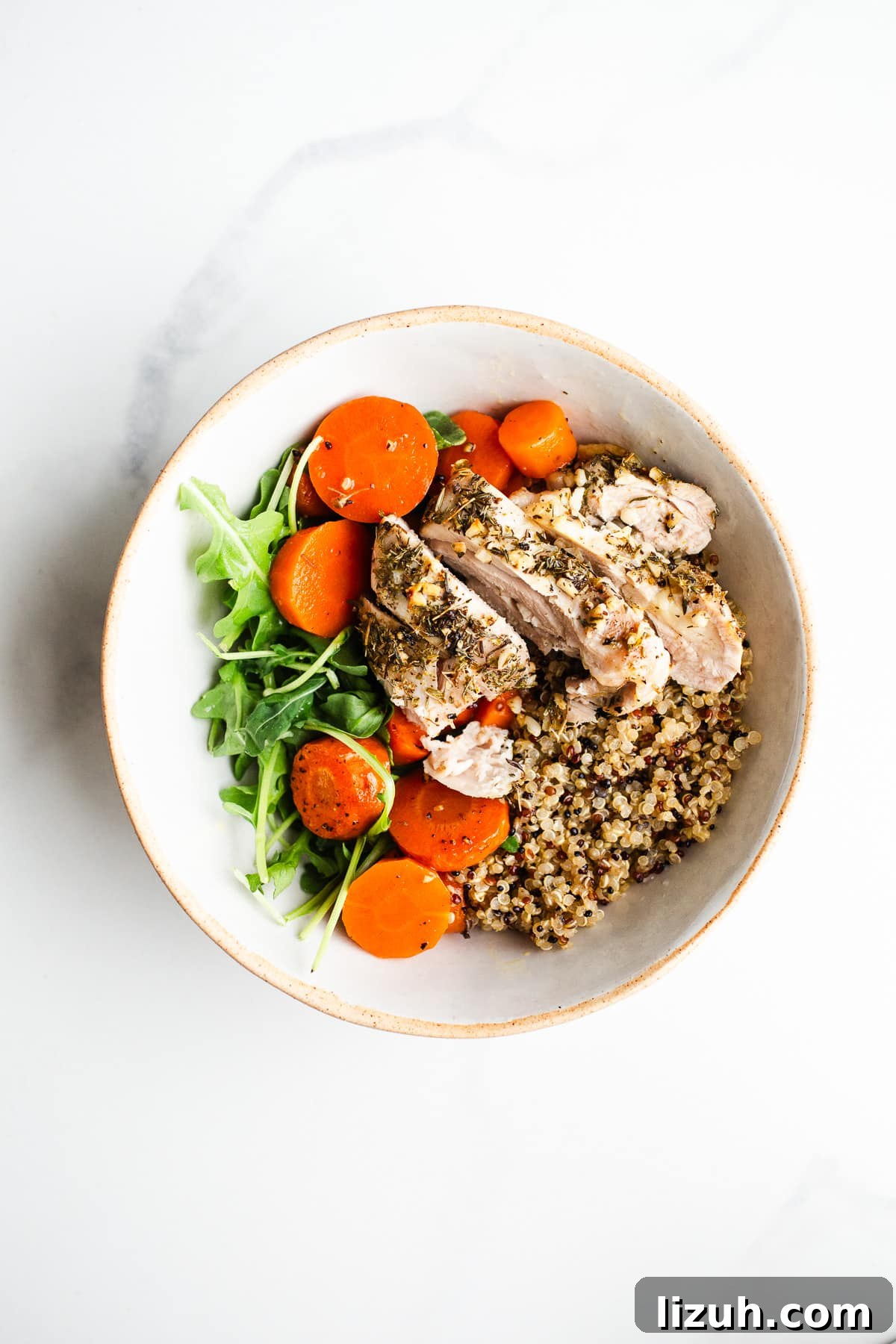 Roasted Carrot and Chicken Quinoa Bowl with Lemon-Tahini Drizzle 7 Sliced chicken and roasted carrots on quinoa in a bowl.
