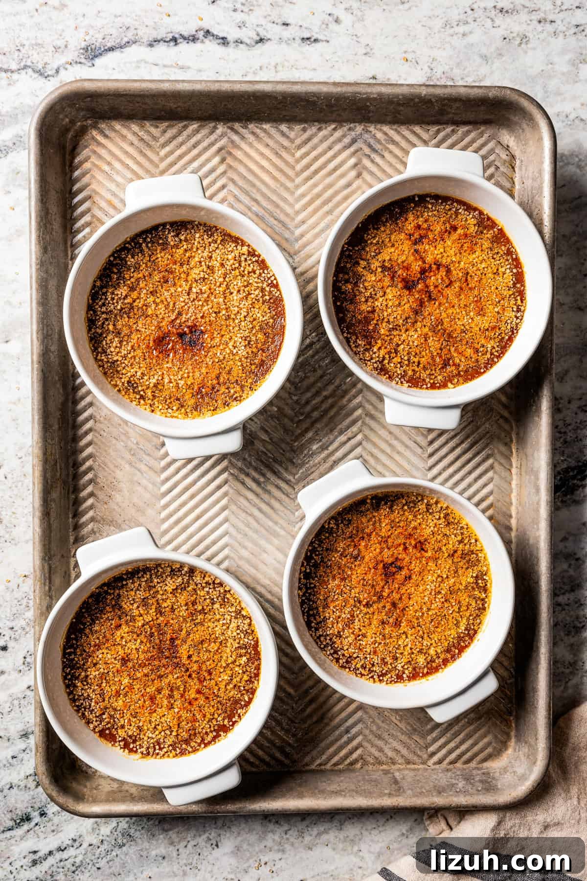 Crème brûlée in ramekins set on a metal tray.