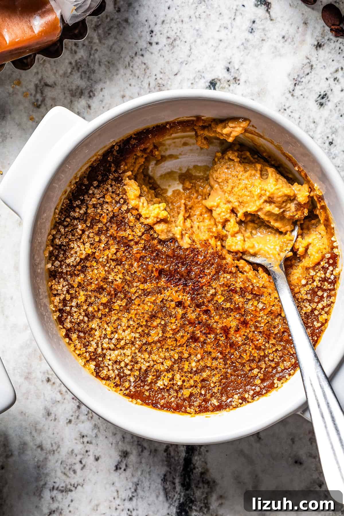 Close-up view of a spoon resting in a ramekin of coffee crème brûlée.