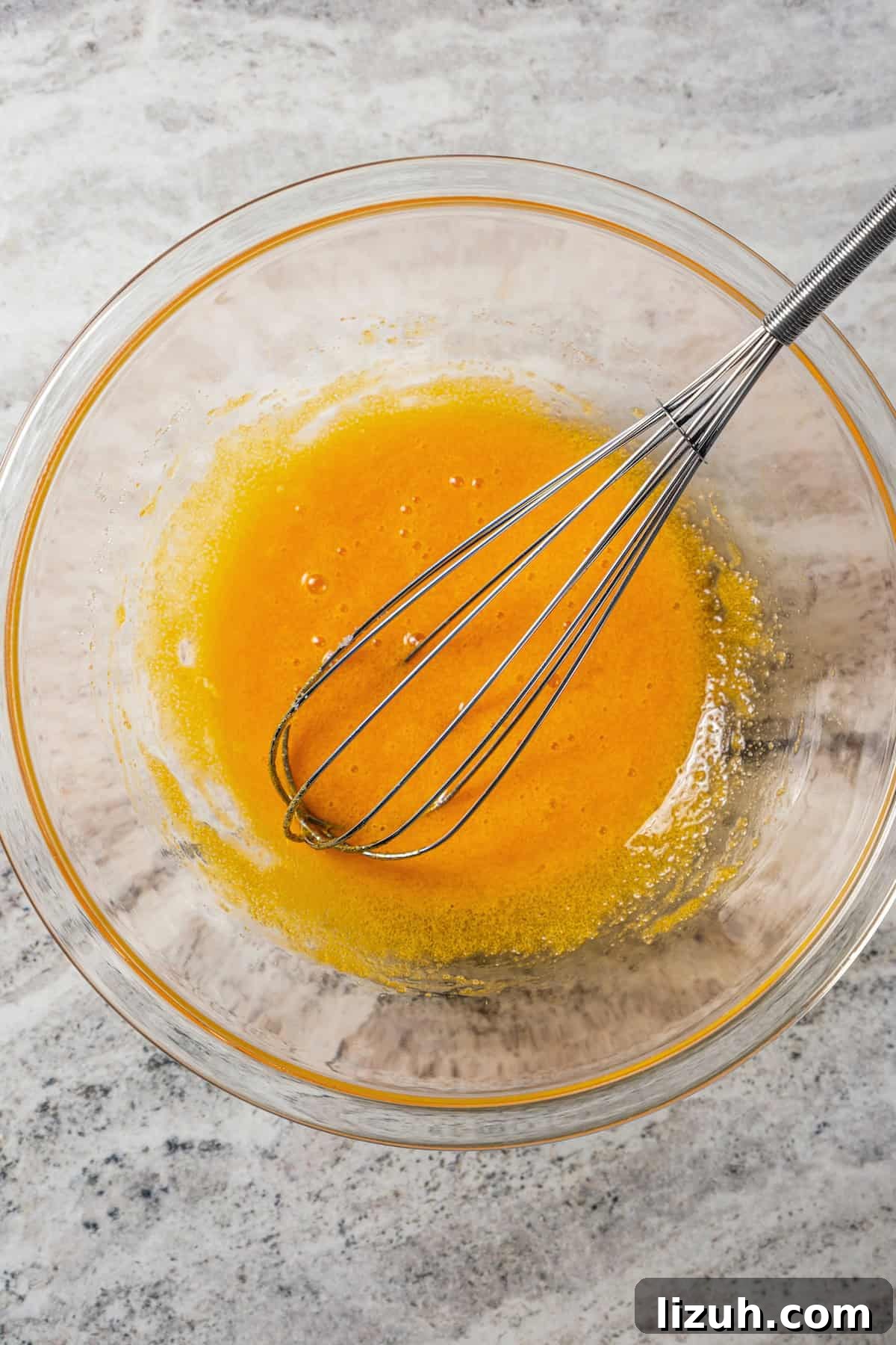 Sugar whisked with egg yolks in a bowl.