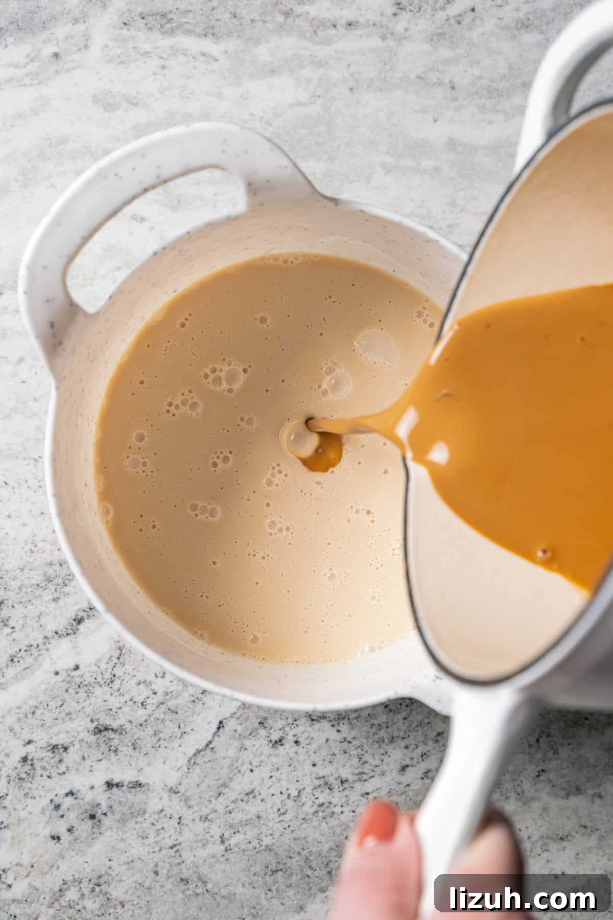 Caramel being poured into coffee cream in a white bowl.