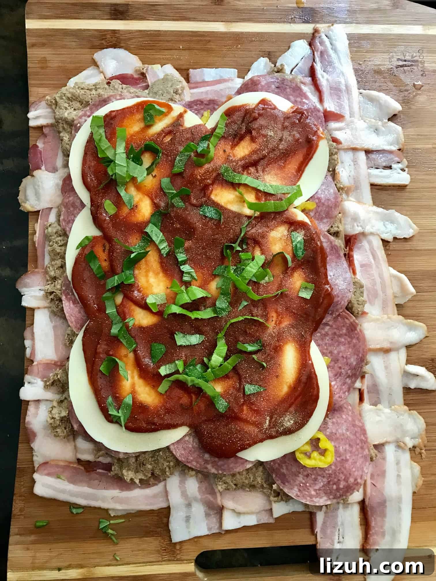 Bacon Explosion Pizza: Stuffed Crust Pizza Fatty Recipe 4 Bacon weave topped with cheese and sauce on wooden cutting board overhead shot