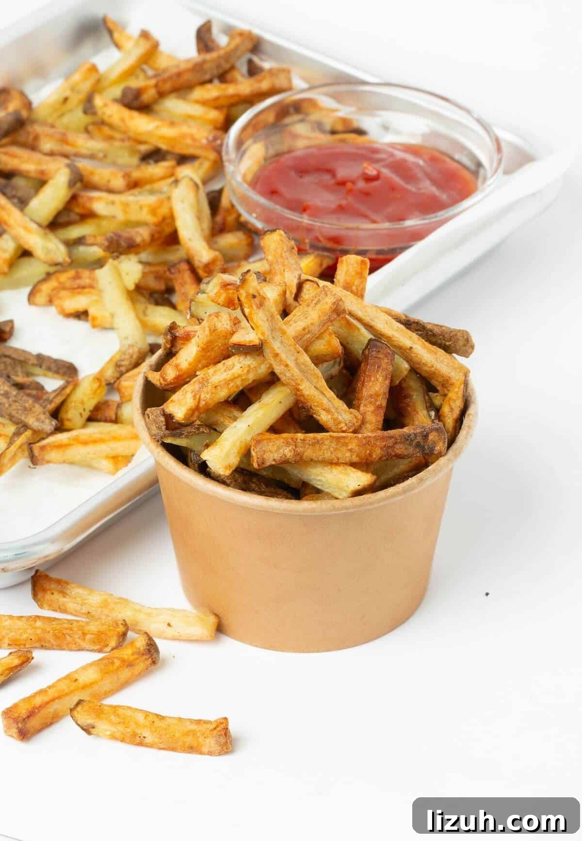 Crispy Air Fryer French Fries: Perfect Golden Recipe 12 air fryer french fries in small paper bowl with baking tray and bowl of ketchup