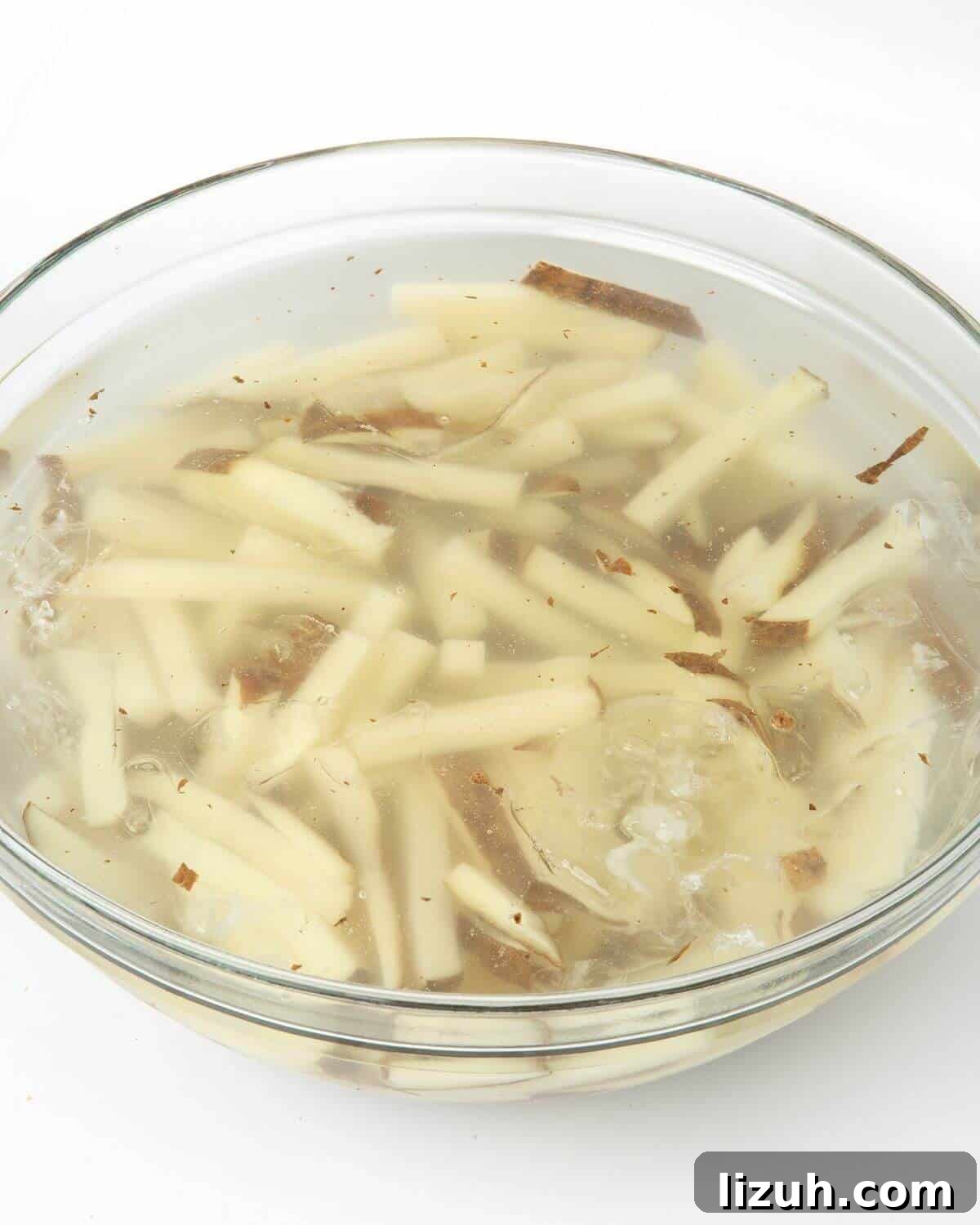 Crispy Air Fryer French Fries: Perfect Golden Recipe 7 cut potatoes soaking in bowl of water