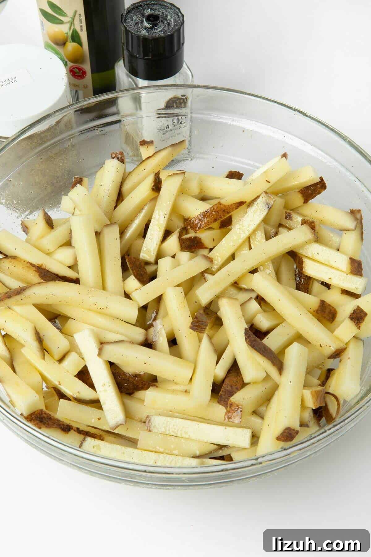 Crispy Air Fryer French Fries: Perfect Golden Recipe 9 cut potatoes in glass mixing bowl