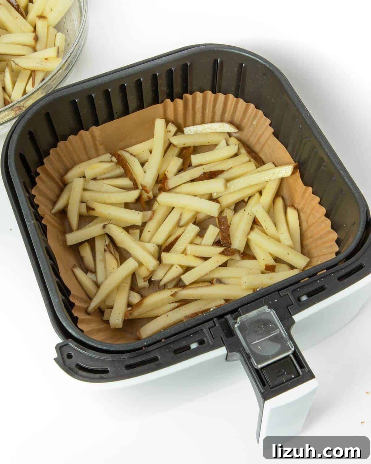 Crispy Air Fryer French Fries: Perfect Golden Recipe 10 cut potatoes in air fryer tray with paper liner
