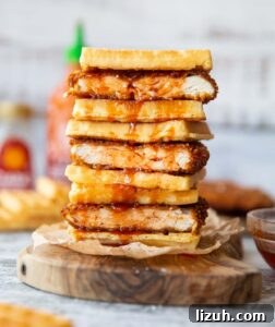 cornflake chicken waffle sandwich 4 cornflake fried chicken waffle sandwiches stacked on each other on wooden board with sriracha maple dripping down