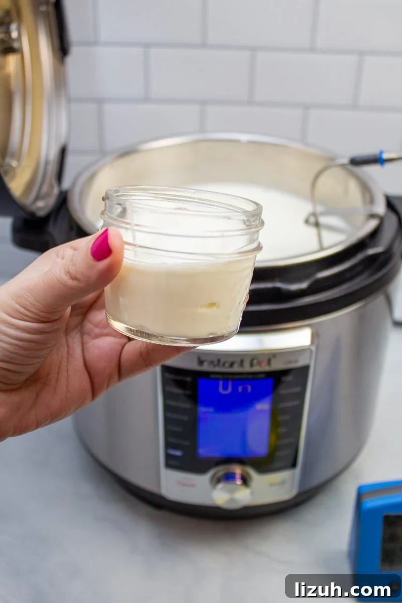 How to Make Creamy Instant Pot Yogurt at Home 11 Small glass jar of yogurt in front of an Instant Pot full of milk.