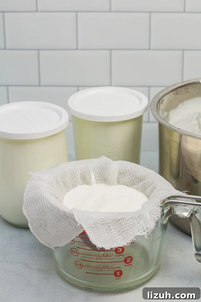 How to Make Creamy Instant Pot Yogurt at Home 14 Glass jars of freshly made yogurt with an Instant Pot and a cheesecloth-lined mesh strainer draining yogurt to thicken.